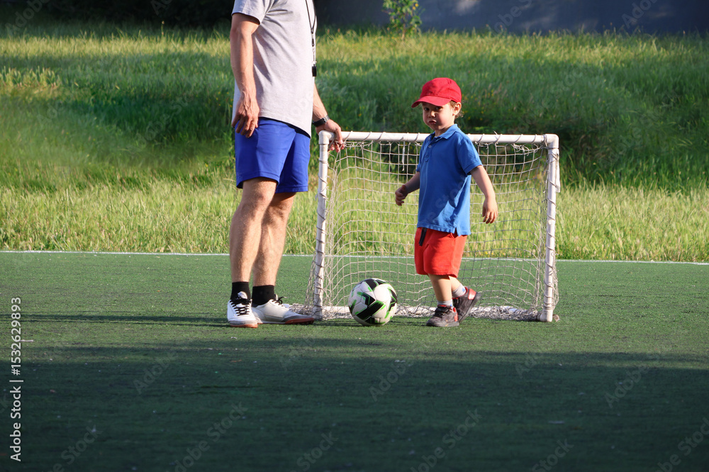 Obraz premium little three-year-old boy plays football at a sports school with a coach.