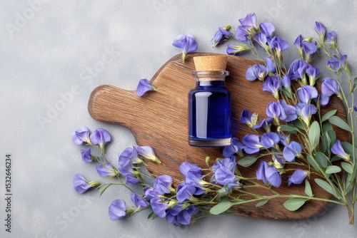 Aromatherapy Essential Oil Bottle with Blue Pea Flowers on Wooden Cutting Board . Generative AI