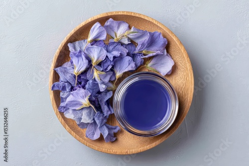 Blue Pea Petal Cream Jar with Herbal Flowers in Wooden Plate Top View . Generative AI