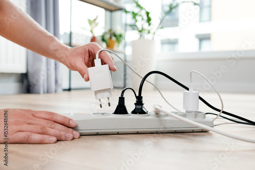 Photos Person is plugging in a device to a power strip