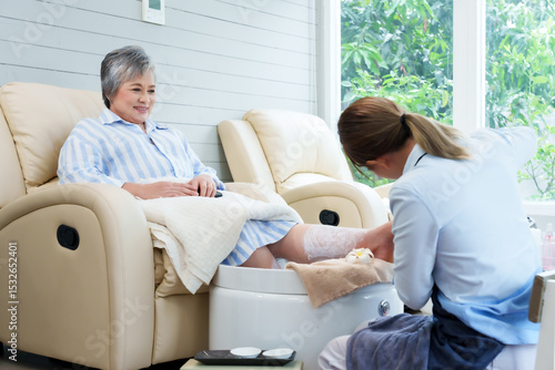 Billede på lærred Spa technician providing foot care treatment to elderly woman at cozy nail spa s