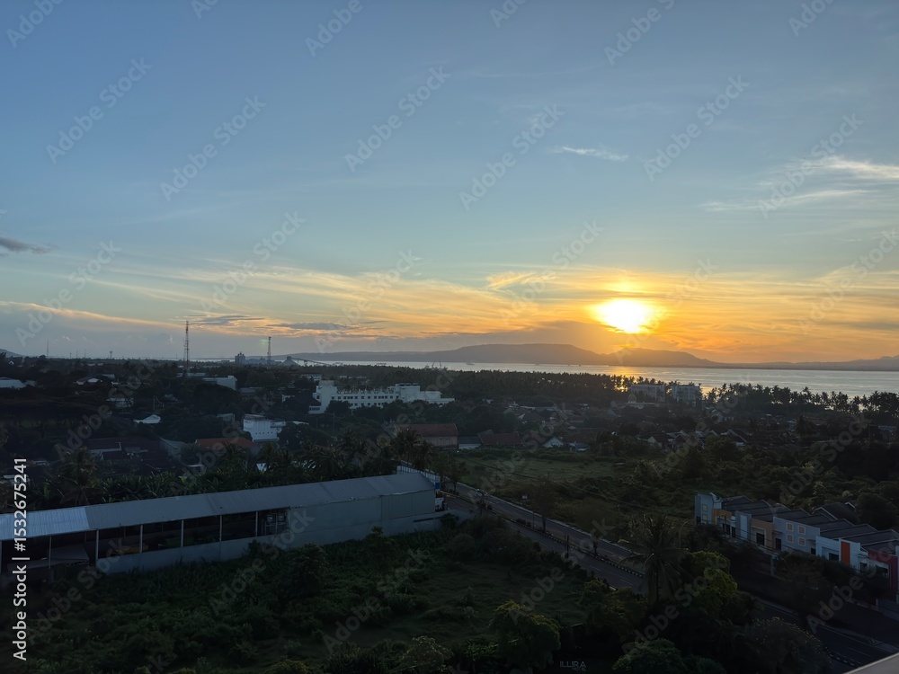 Obraz premium Panoramic sunrise over a city and bay with a vibrant yellow sky. 