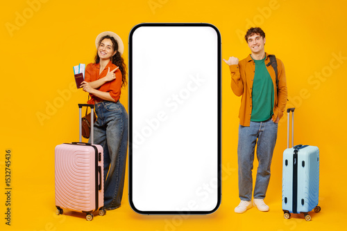 Confident European couple standing next to giant smartphone with white blank screen, appropriate for travel app displays, banner