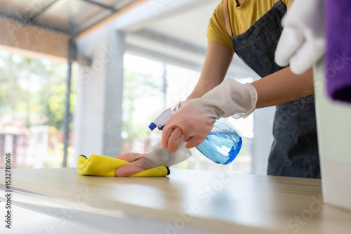 
A woman is cleaning a counter with a yellow cloth and a spray bottle. The counter is made of granite and is in a kitchen

