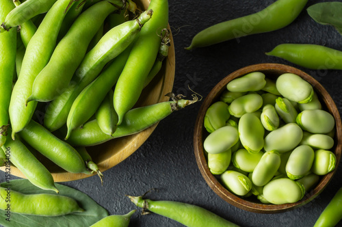 Fresh broad beans with pod in bowl on dark rustic background, healthy food