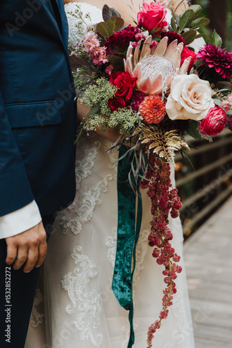 Canvas Print Close up of bride and groom holding vibrant cascading wedding bouquet with king