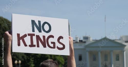 A protester holds a “NO KINGS” sign in front of the White House, referencing concerns about presidential overreach.