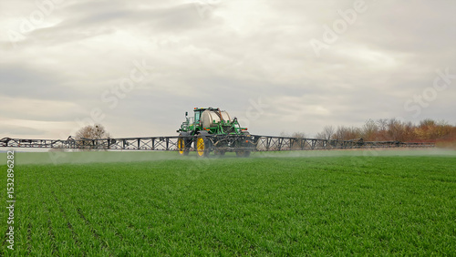 Fotografie Agricultural sprayer tractor working on green crop field