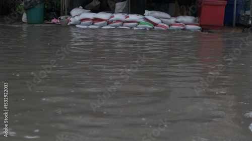 A flooded street with a pile of bags on the ground. The bags are red and white. The water is murky and the bags are floating