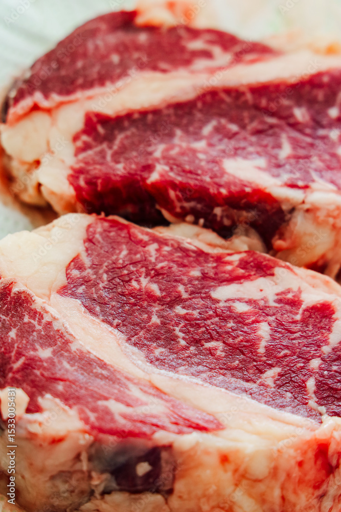 Obraz premium High-quality marbled beef steaks ready for grilling in a kitchen setting