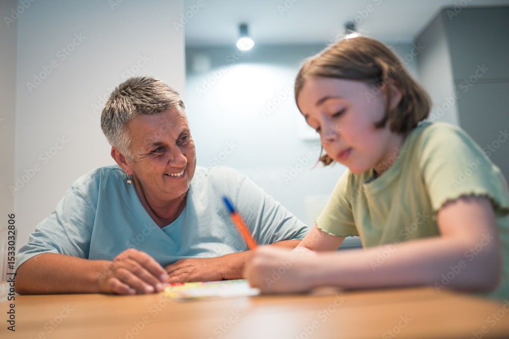 A portrait of grandmother and granddaughter doing homework together at home.
A portrait of grandmother and granddaughter doing homework together at home.