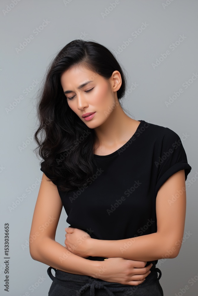 Young asian female in black t-shirt experiencing abdominal pain Young asian female in black t-shirt experiencing abdominal pain