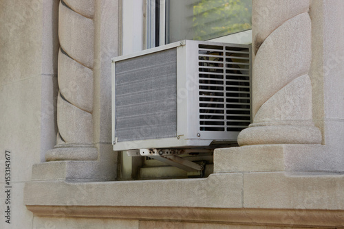 Fotografie exterior view of air conditioning window unit extruding from the window sill wit