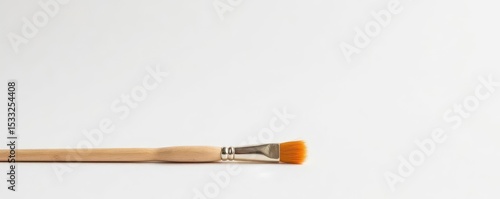 A tiny paintbrush, bristles pointed downwards, sits alone against a stark white backdrop , painting, white background, single
