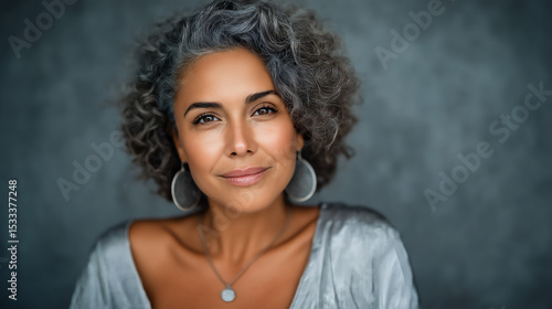 Elegant and beautiful mature Hispanic woman with soft curly hair and smooth healthy skin, skincare concept