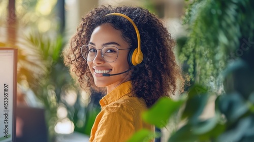 Smiling Woman with Headset in Office Surrounded by Indoor Plants