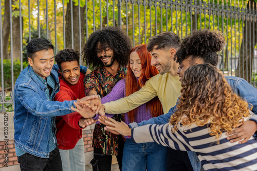 Фотография Happy multi ethnic friends joining hands in a park