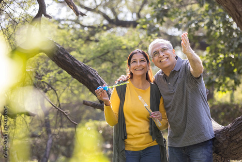 Senior couple blowing bubbles at park
