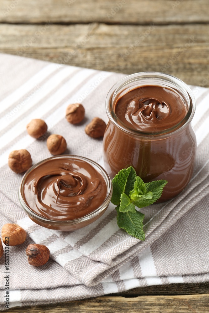 Tasty chocolate spread, hazelnuts and mint on wooden table Tasty chocolate spread, hazelnuts and mint on wooden table