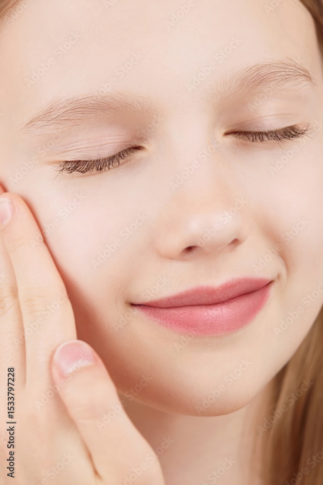Obraz premium Portrait of smiling cheerful girl doing beauty routine, face massage, applies skin product. Advertisement of self-care products for teenagers. Blonde girl with closed eyes in studio on pink background