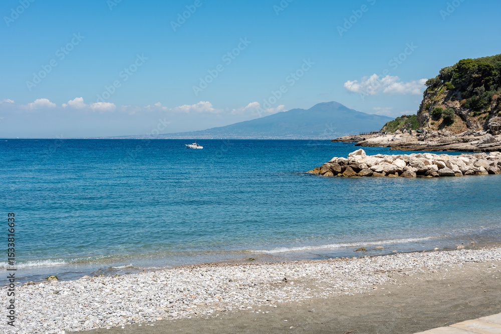 Fototapeta premium Beach of the village Marina di Puolo in Massa Lubrense with Vesuvius in the distance, the blue waters in the Sorrento peninsula Naples. Italy
