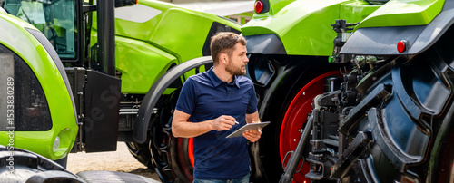 Fotografie Male technician inspecting agricultural machinery with digital device outdoors
