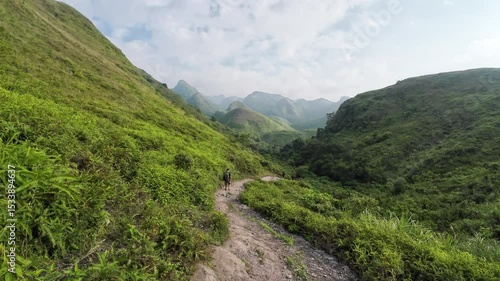 Wallpaper Mural Tourist hiking on rugged dirt trail surrounded by lush green forest on hill in countryside Torontodigital.ca