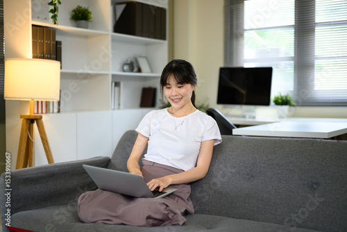 Free Download Young woman relaxing with laptop computer in living room - GFXLoad