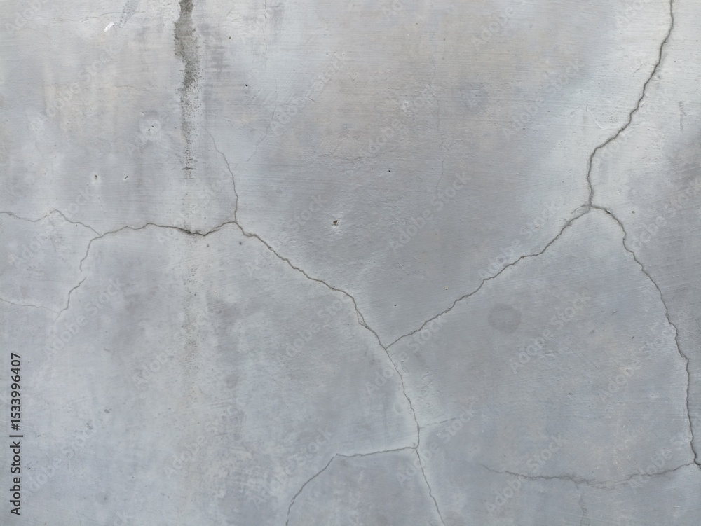 Obraz premium Cracked Grey Concrete Texture. A close-up of a light grey concrete surface with distinct, intricate crack patterns and subtle discoloration