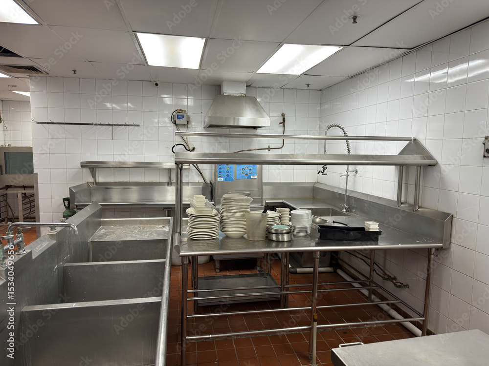 Obraz premium Clean stainless steel kitchen setup with washing stations and ample counter space for food preparation and plates