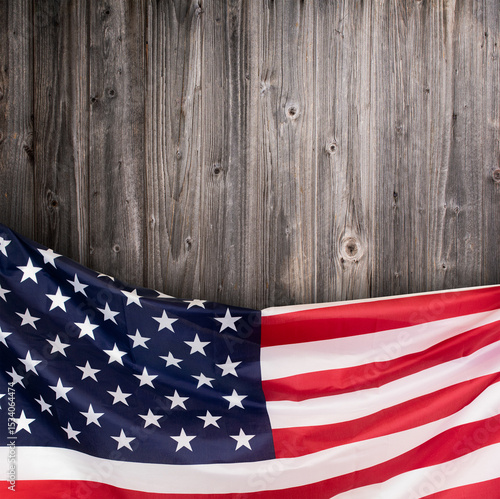The United States flag draped along the bottom edge of a rustic wooden background. Stock photo.