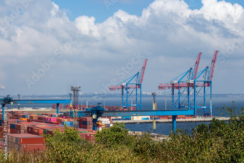 A wide shot shows the busy Port of Odesa Ukraine featuring towering gantry cranes moving numerous brightly colored shipping containers, illustrating maritime industry and international commerce.
