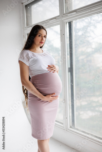 Pregnant woman in dress with very long hair on white background. Dreamy tender girl expecting a child. Portrait of beautiful pregnant woman in white shirt, smile. Window Free Download Pregnant woman in dress with very long hair on white background. Dreamy tender girl expecting a child. Portrait of beautiful pregnant woman in white shirt, smile. Window - GFXLoad