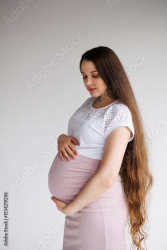 Pregnant woman in dress with very long hair on white background. Dreamy tender girl expecting a child. Portrait of beautiful pregnant woman in white shirt, smile. Window Free Download Pregnant woman in dress with very long hair on white background. Dreamy tender girl expecting a child. Portrait of beautiful pregnant woman in white shirt, smile. Window - GFXLoad