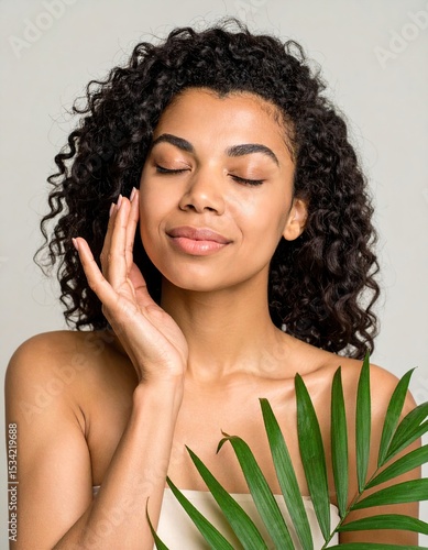 Woman with curly hair, touching her face, peaceful expression, palm leaf