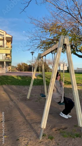 Young woman swinging on a hillside swing at sunset with sea view, slow motion