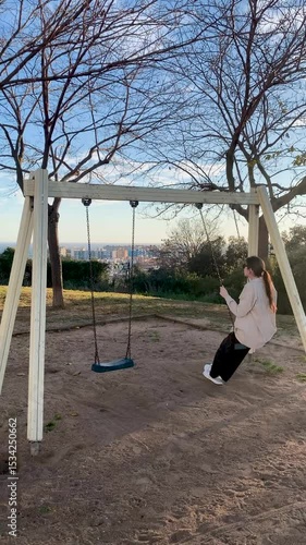 Young woman swinging on a hillside swing at sunset with sea view, slow motion