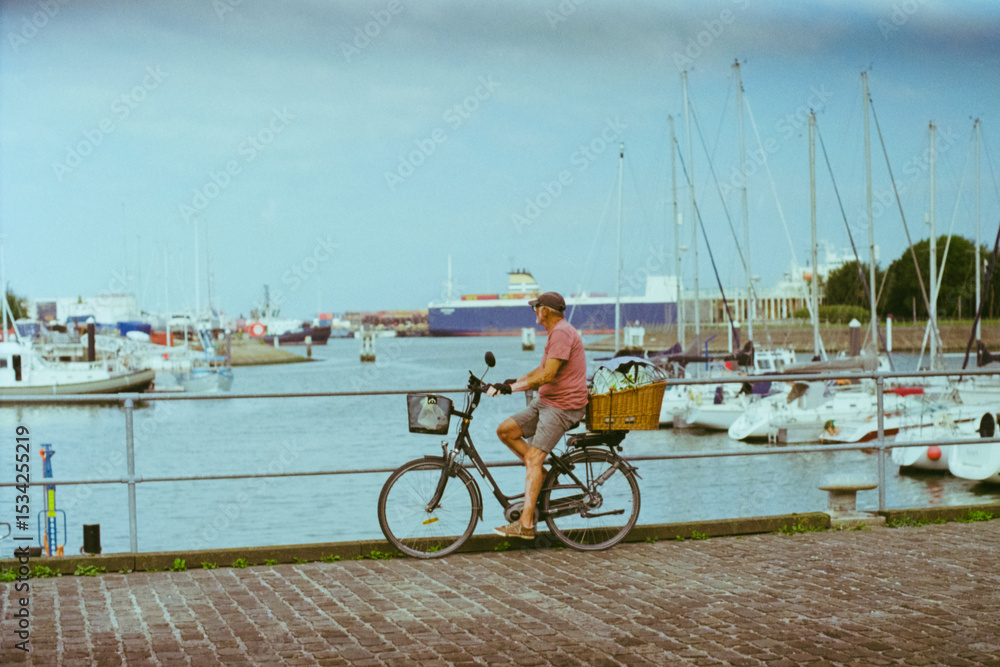 Fototapeta premium an old person riding a bike along the pier on the Belgian coast, in warm tones shot on film