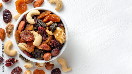 Fototapeta Naklejka Na Ścianę i Meble -  A top view of a white bowl filled with mixed nuts and dried fruits on a white textured background