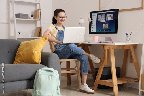 Teenage girl with laptop working online at home