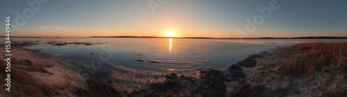 Breathtaking Sunset Over Calm Waters With Reflections and Silhouetted Grass at a Serene Lakeshore in the Early Evening