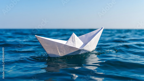 White paper boat floating on blue ocean water