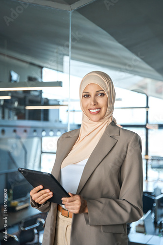 Free Download Vertical portrait at camera Arab young woman ceo analyst manager using tablet for business work, learning or communication. Middle Estern businesswoman in hijab headscarf working on gadget in office - GFXLoad
