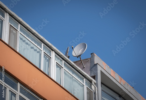 Slika na platnu A old satellite dish on the roof of a apartment.