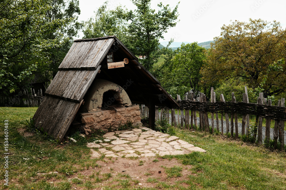 Outdoor traditional Serbian clay oven with stone base and wooden roof in a village museum Outdoor traditional Serbian clay oven with stone base and wooden roof in a village museum