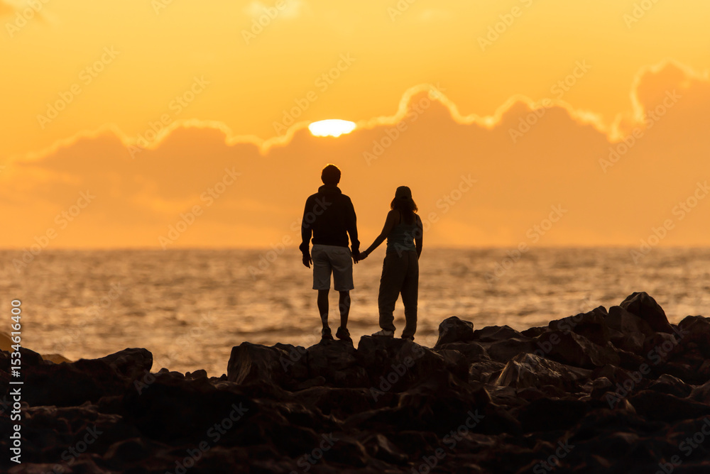 Silhouette of a couple watching the sunset in a cloudy landscape. Travel lifestyle concept. Silhouette of a couple watching the sunset in a cloudy landscape. Travel lifestyle concept.