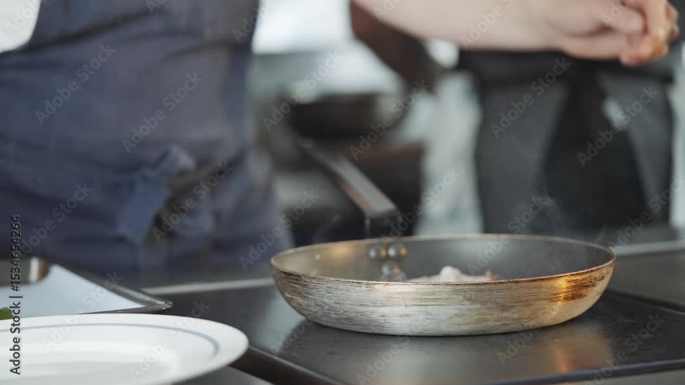 A man is cooking food in a pan. The pan is on a table and there are utensils nearby A man is cooking food in a pan. The pan is on a table and there are utensils nearby