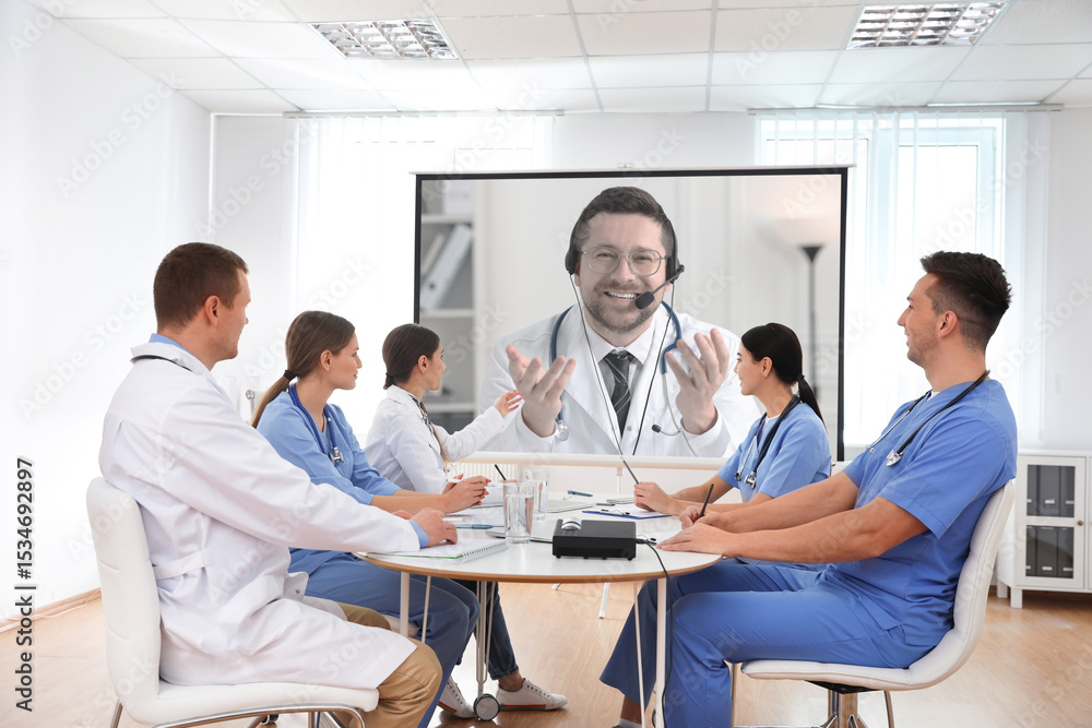 Fototapeta premium Team of doctors using video projector during conference indoors. Speaker on projection screen