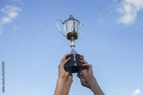 Teenage hands holding winning grand final trophy in the sky