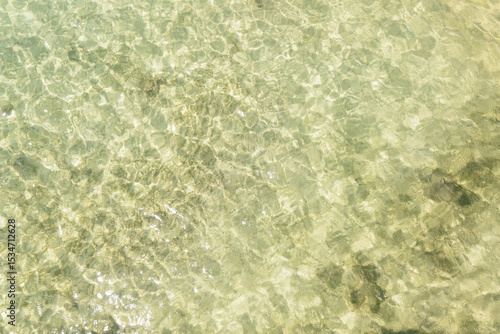 Looking down on clear water rippling over sand